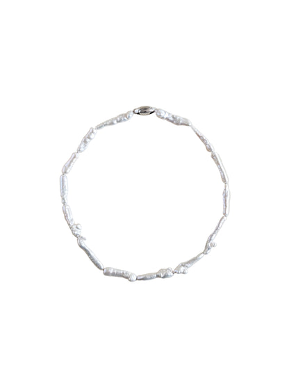 A pearl choker made of irregular keshi biwa pearls on a plain beige background.