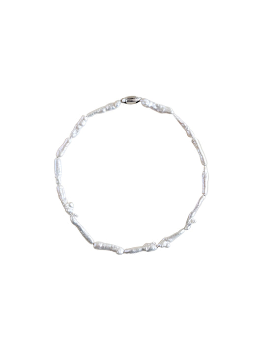 A pearl choker made of irregular keshi biwa pearls on a plain beige background.