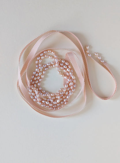 Pink ribbon with pearls on a light gray background