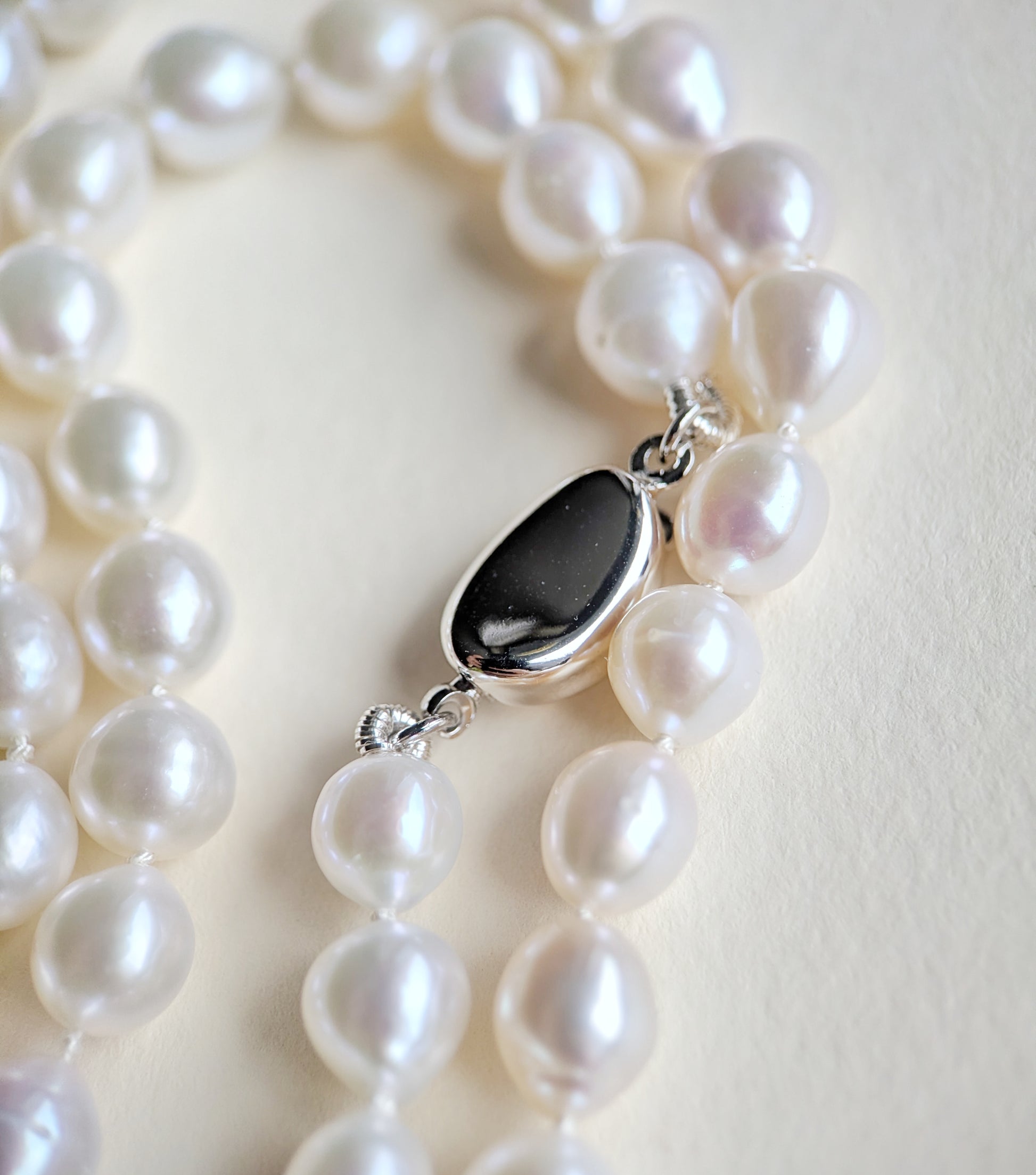 Pearl necklace with a silver clasp on a light background
