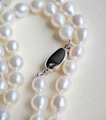 Pearl necklace with a silver clasp on a light background