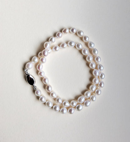 Pearl necklace on a light gray background