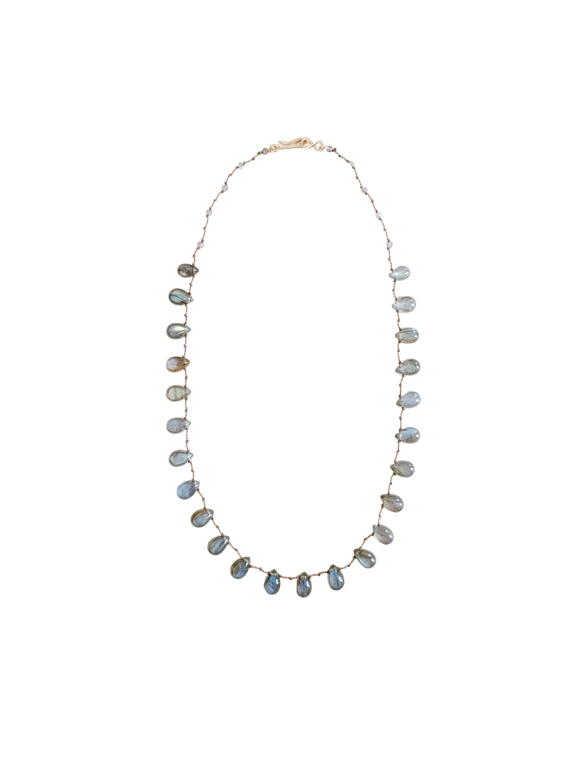 A delicate necklace featuring labradorite teardrop beads against a  solid off-white background.