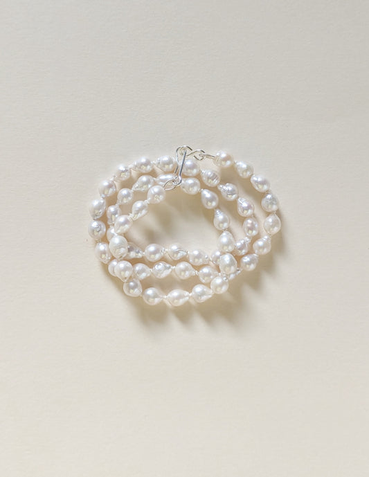 Pearl necklace or bracelet on a light beige background