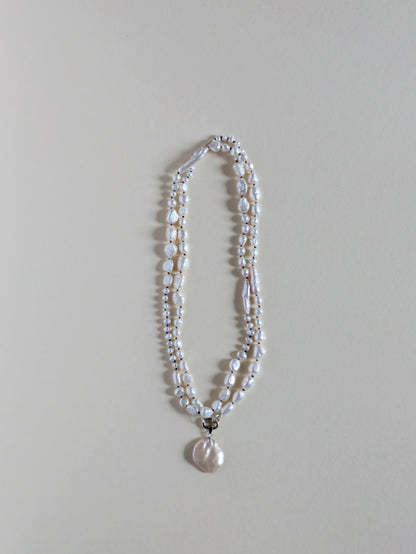 Two strand long pearl necklace with a pendant on a silver clasp.