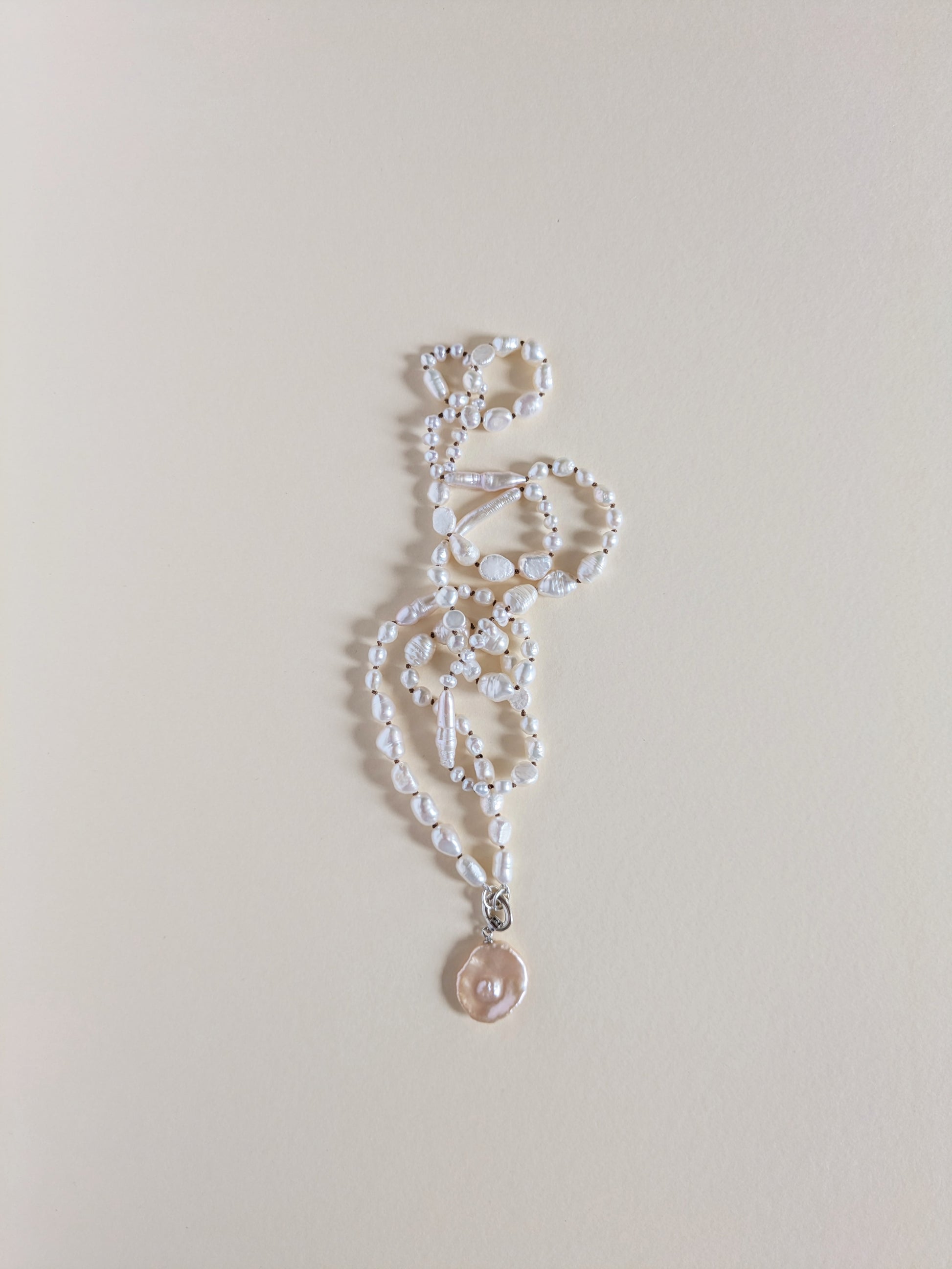 Pearl necklace with a pendant on a light gray background