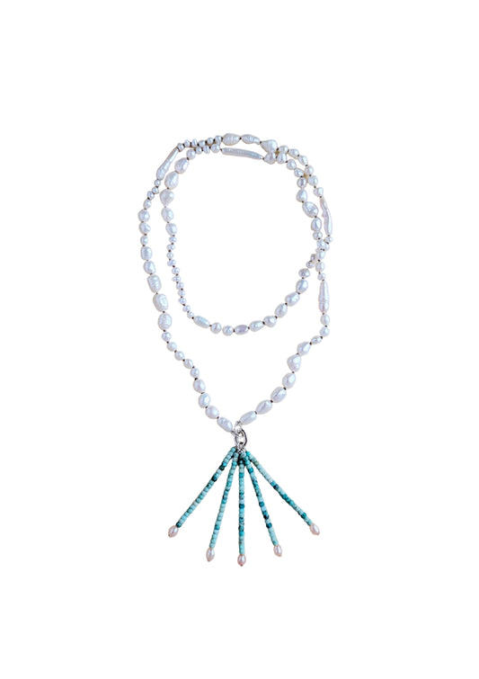 A double-strand necklace featuring irregular white freshwater pearls and a silver-tone clasp, with a drop pendant composed of turquoise and white beads ending in small pearl tips, displayed on a neutral beige background.