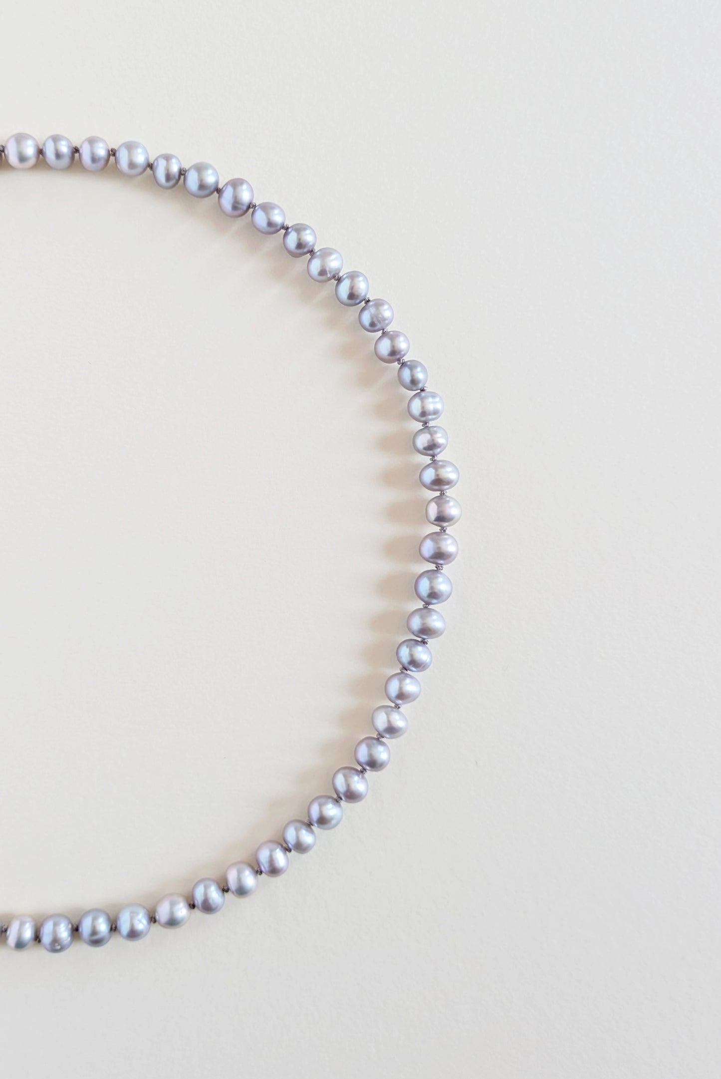 Silver grey pearl necklace on a light beige background