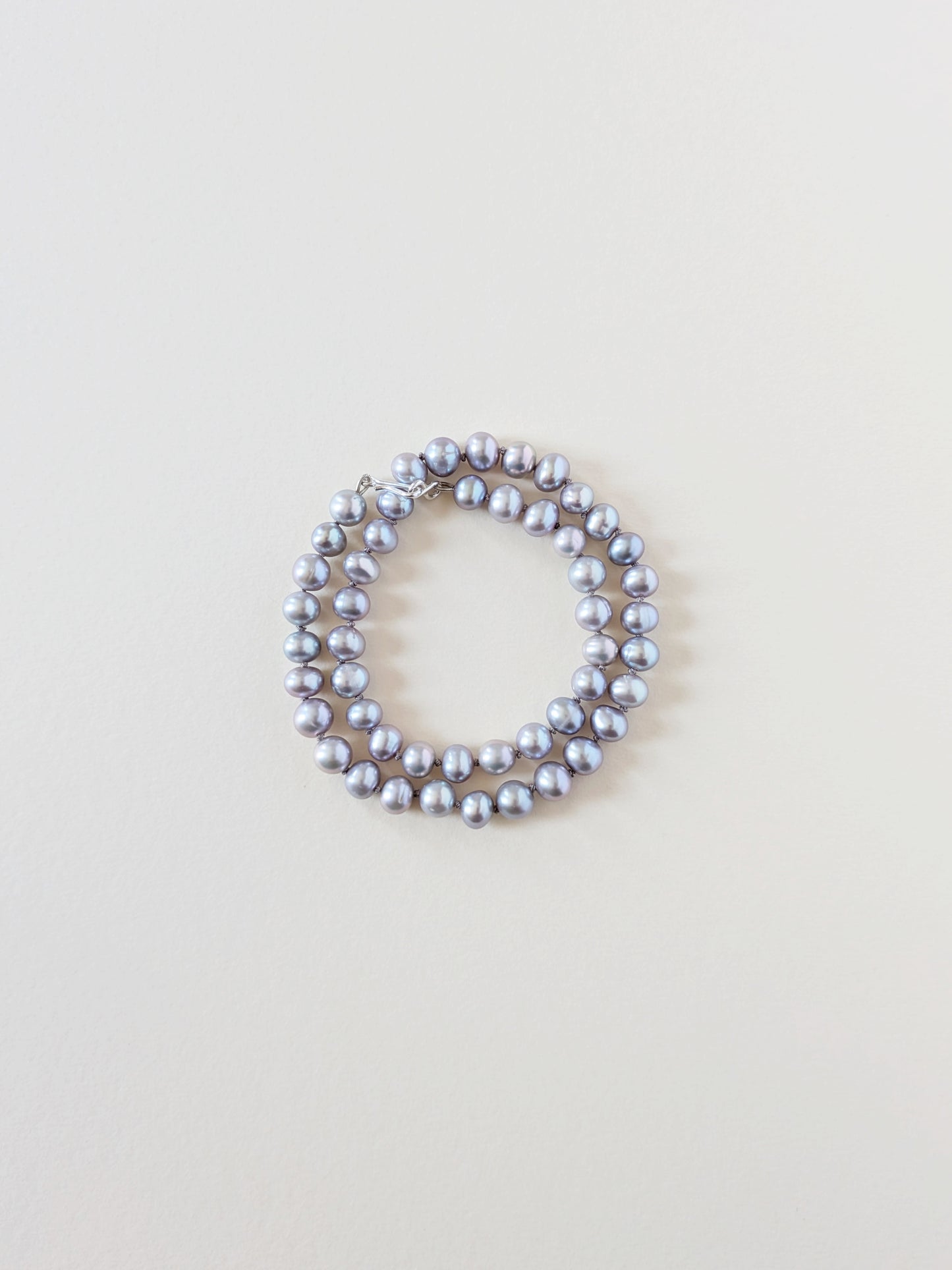 Grey pearl necklace wrapped as a bracelet.
