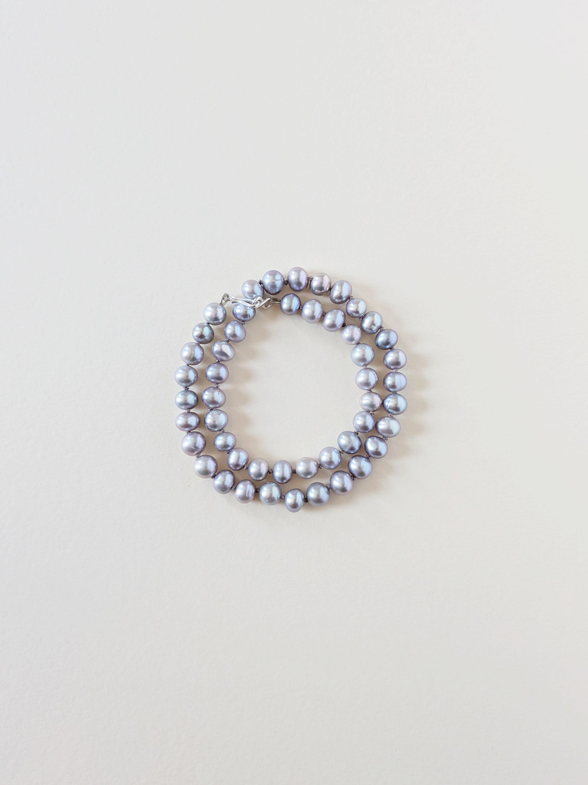 Grey pearl necklace wrapped as a bracelet.