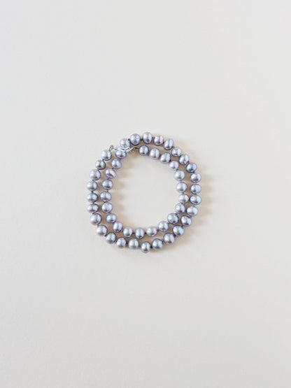 Grey pearl necklace wrapped as a bracelet.