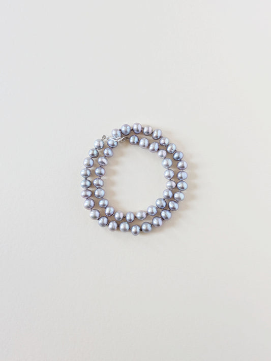 Grey pearl necklace wrapped as a bracelet.
