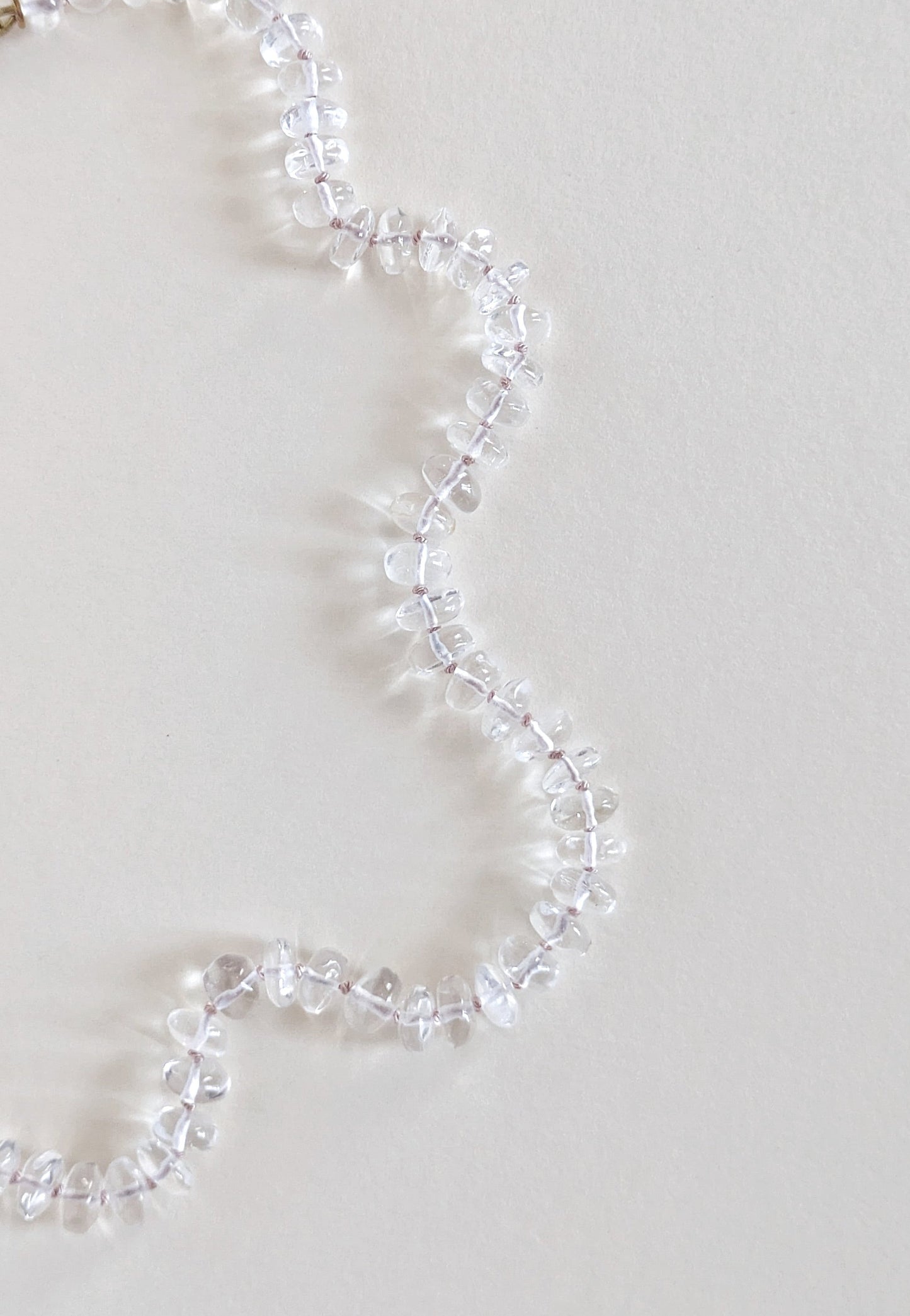 Clear quartz necklace on a light gray background