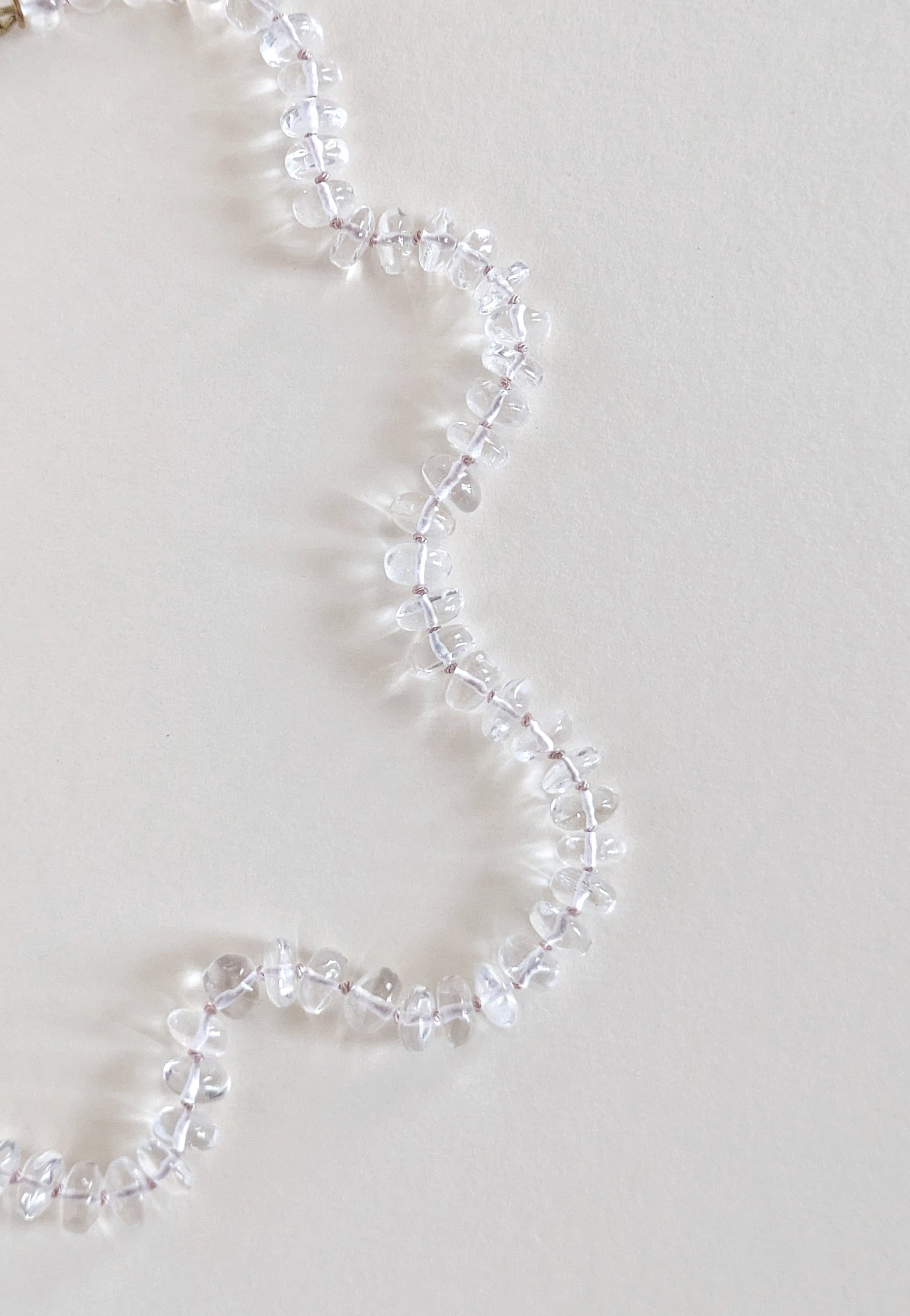Clear quartz necklace on a light gray background