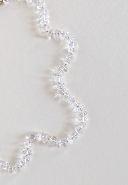 Clear quartz necklace on a light gray background