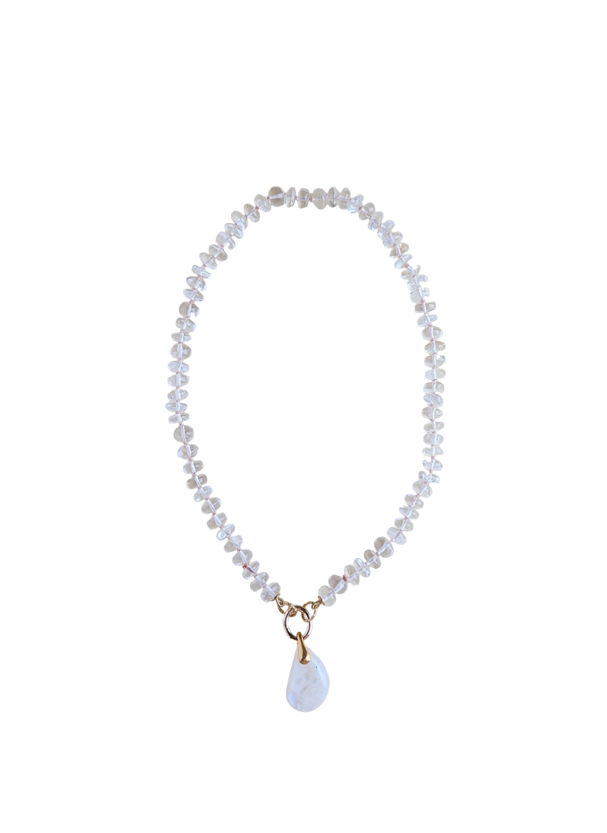 A delicate beaded necklace with clear faceted beads and a small white teardrop moonstone pendant with gold-tone metal accents, displayed on a plain light beige background.