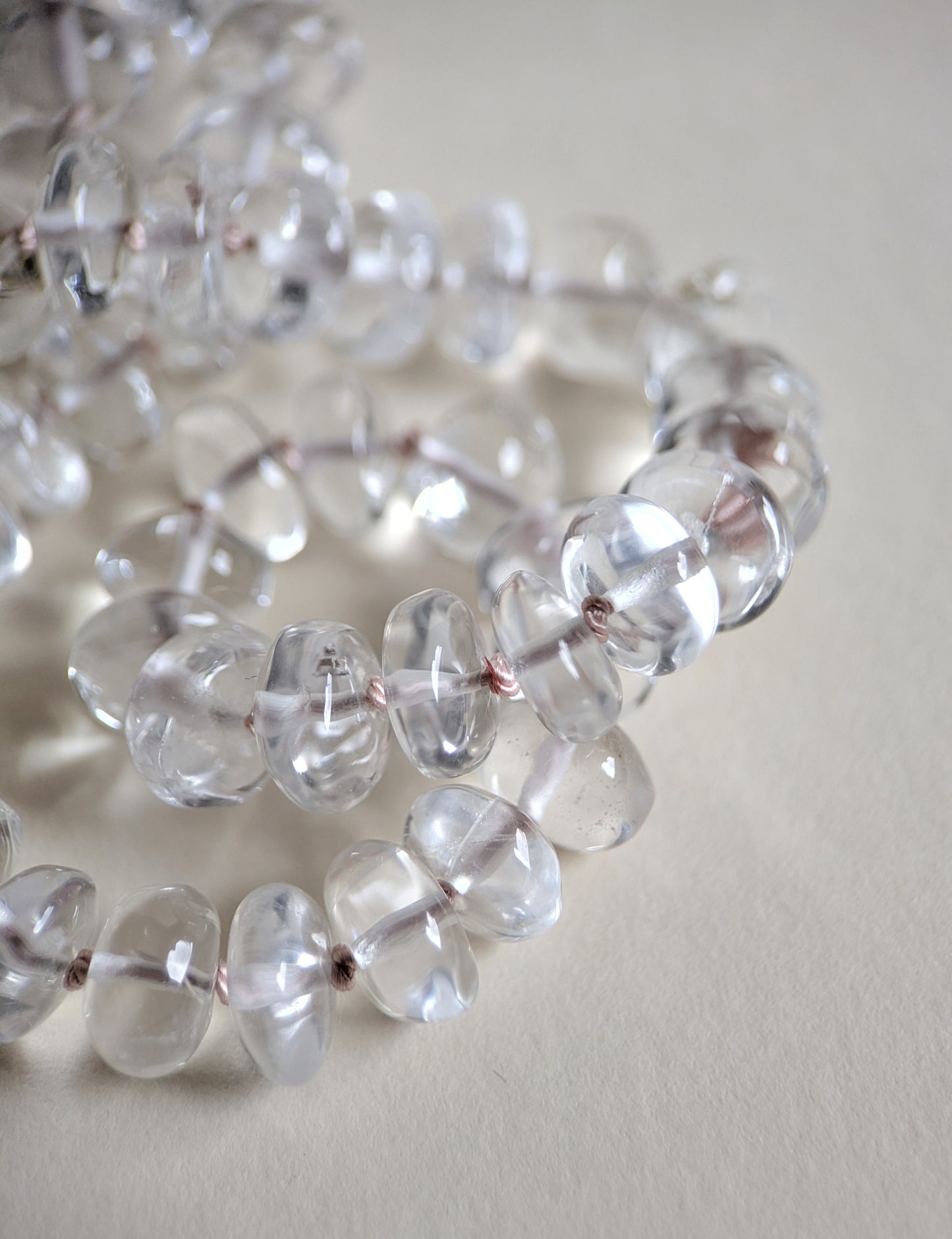 Close-up of clear quartz beads on a light background