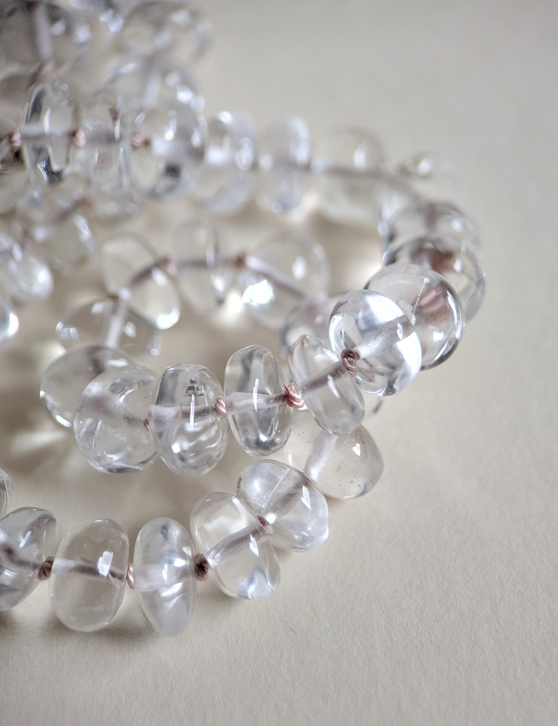 Close-up of clear quartz beads on a light background