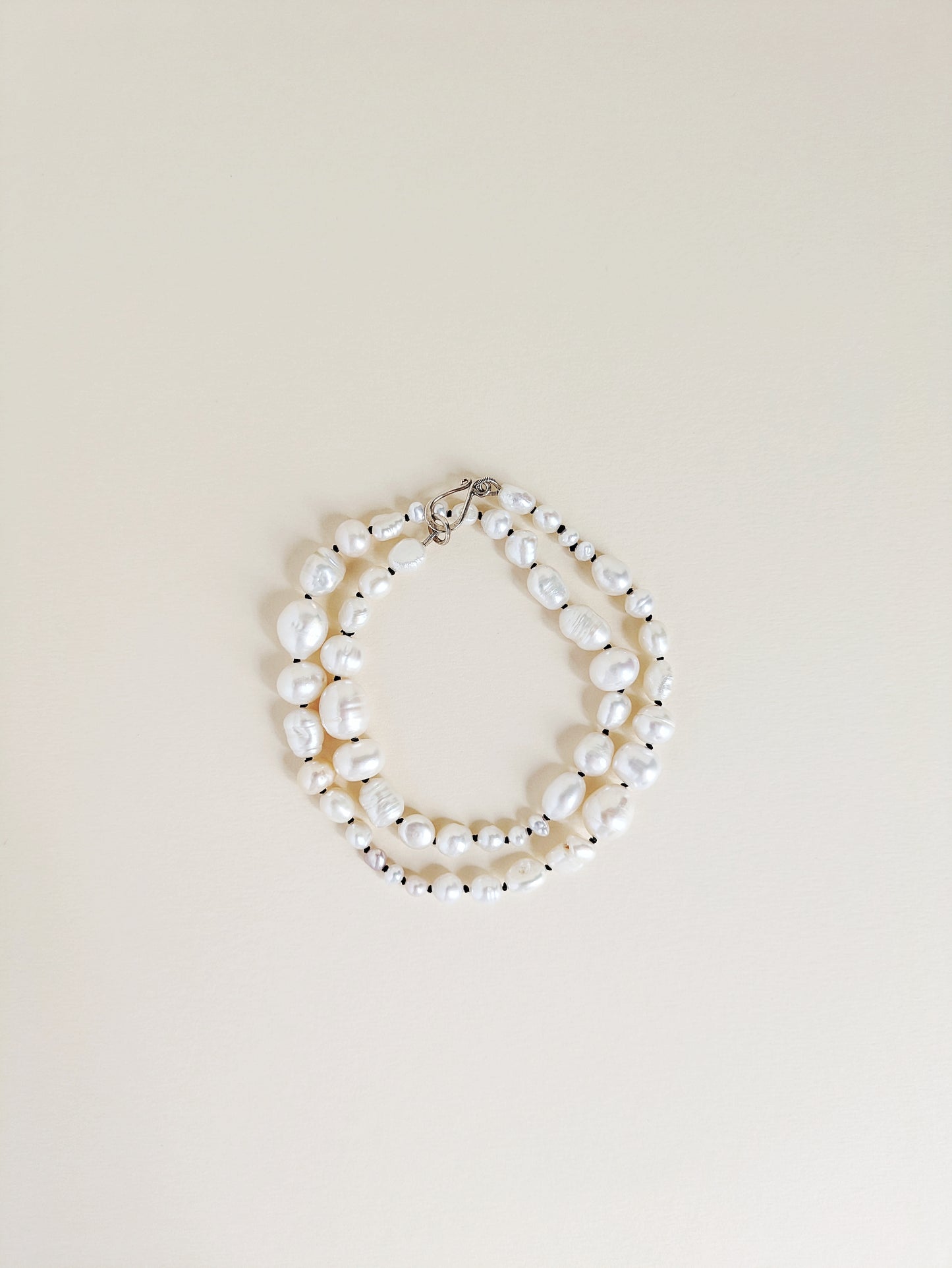 Pearl necklace or bracelet on a beige background
