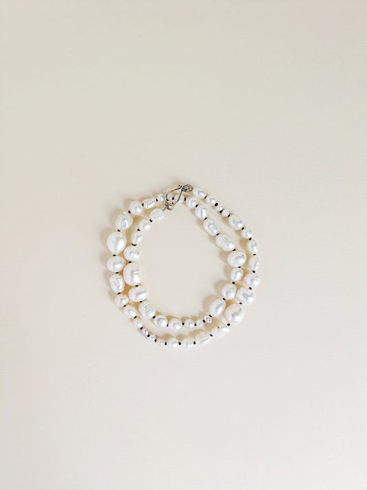 Pearl necklace or bracelet on a beige background