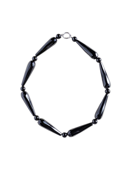 Onyx necklace Drama on a white surface.