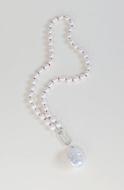 Pearl necklace with a silver clasp and pendant on a light background
