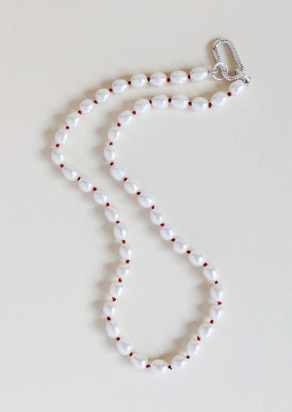 Pearl necklace with red beads on a light beige background