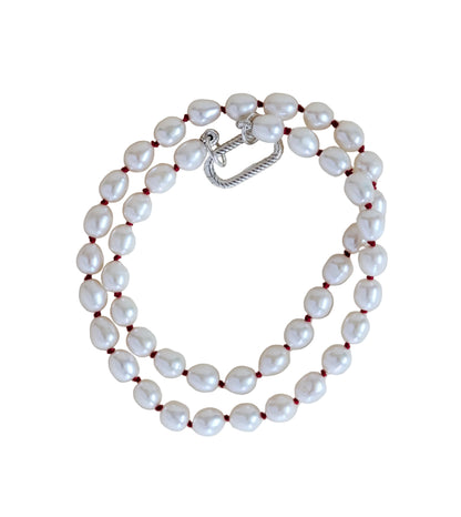 Pearl necklace with a silver clasp on a light beige background