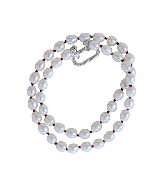Pearl necklace with a silver clasp on a light beige background
