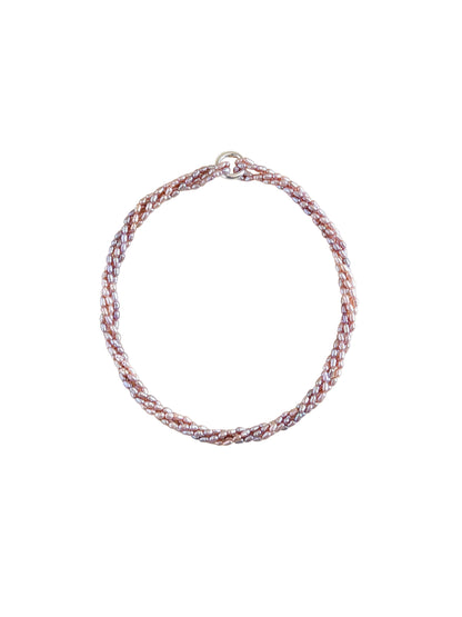 A braided rice pearl multistrand necklace with a silver clasp displayed on a solid beige background.
