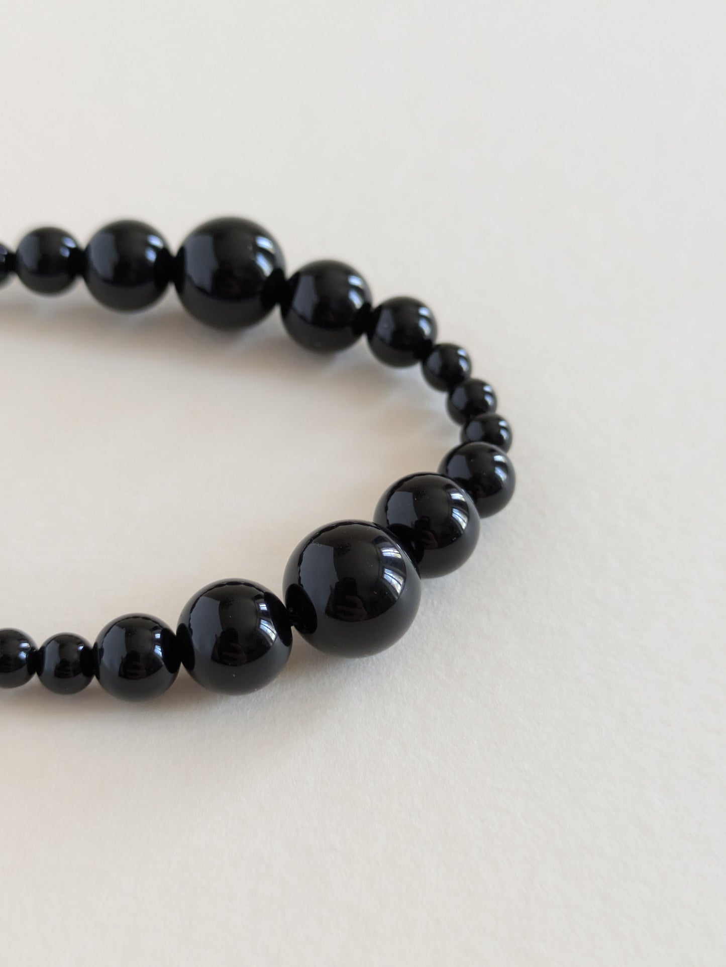 Black beaded bracelet on a light beige background