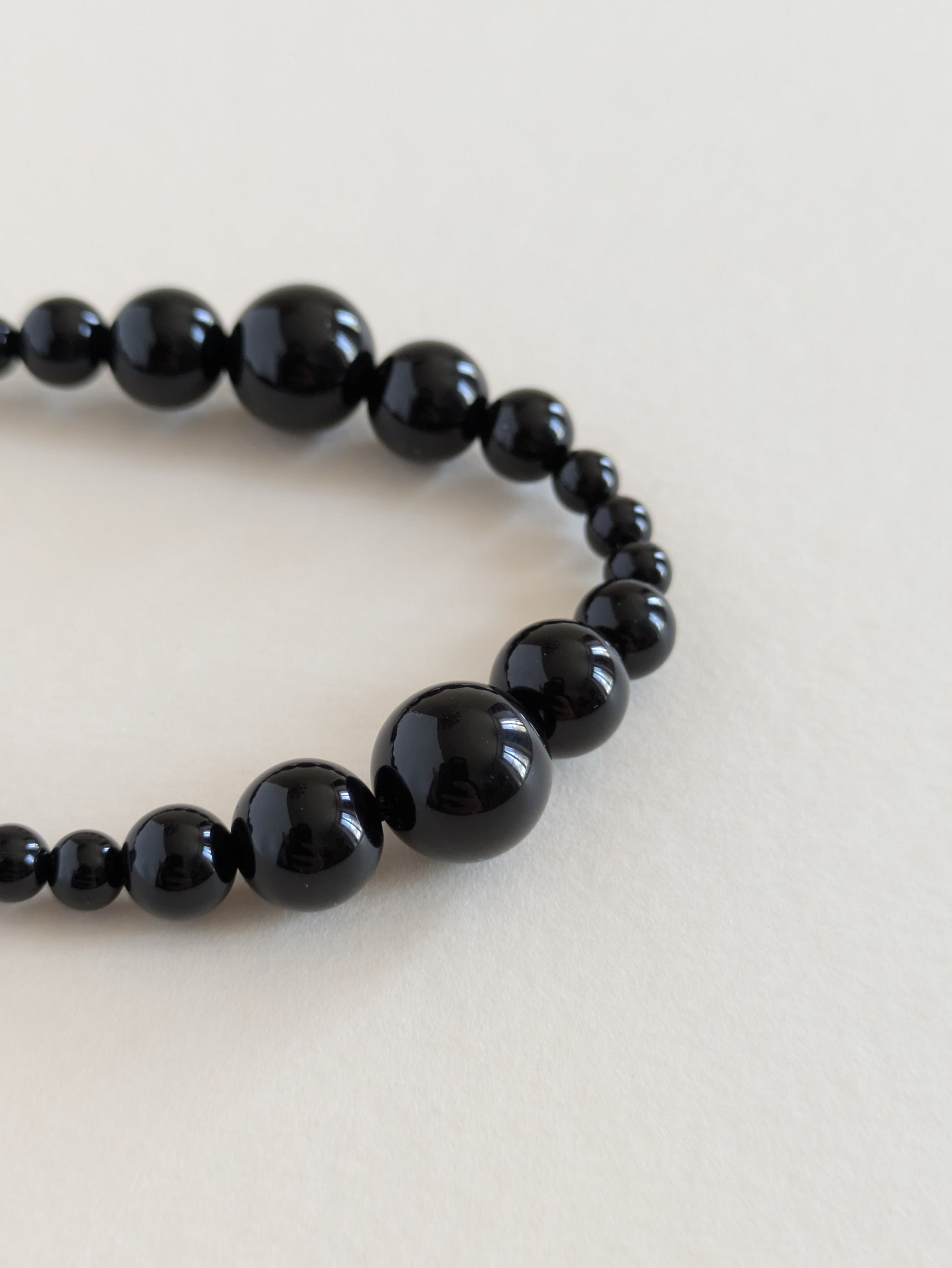 Black beaded bracelet on a light beige background