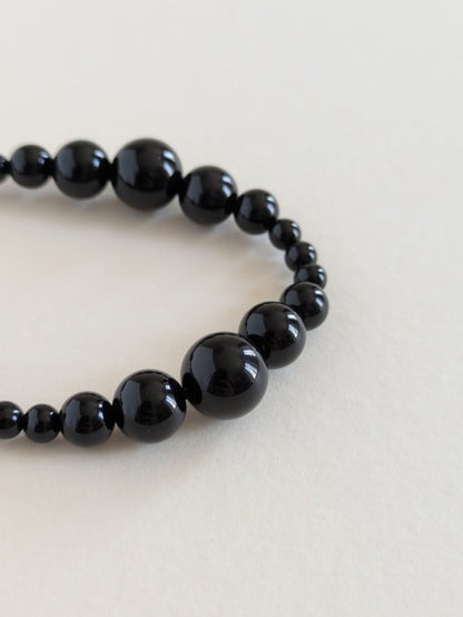 Black beaded bracelet on a light beige background